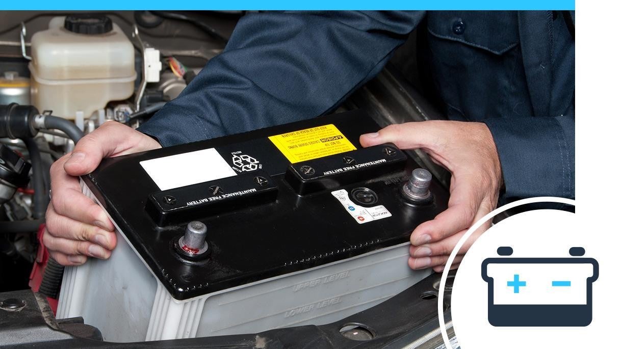 Service technician placing a battery into a vehicle.