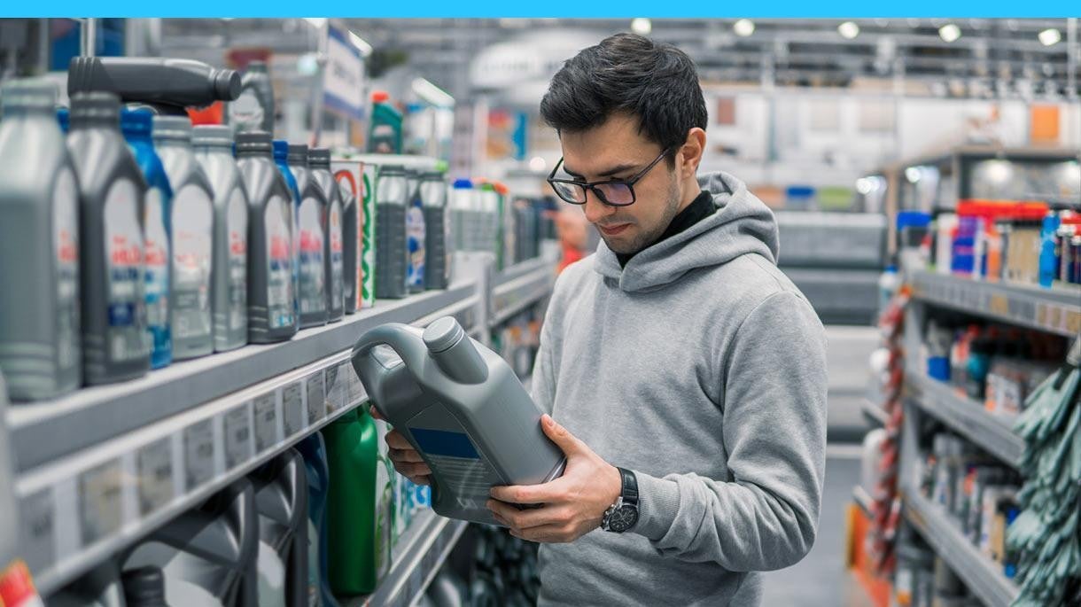 man with glasses reading the back of an oil jug