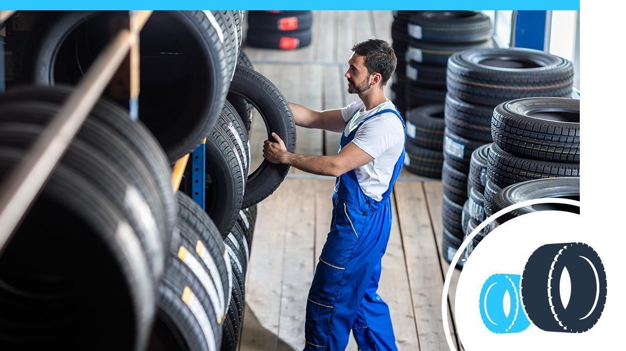 Service technician grabbing a tire off a rack.