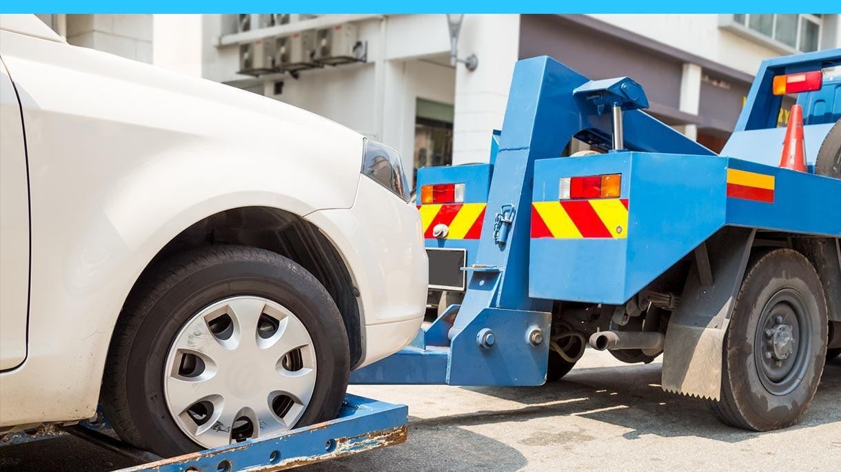 blue tow truck towing a white car