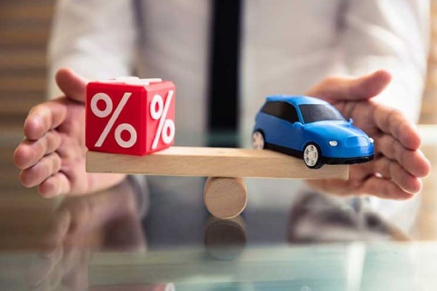 Blue miniature car on a wooden scale with a red dice with percentage signs on it